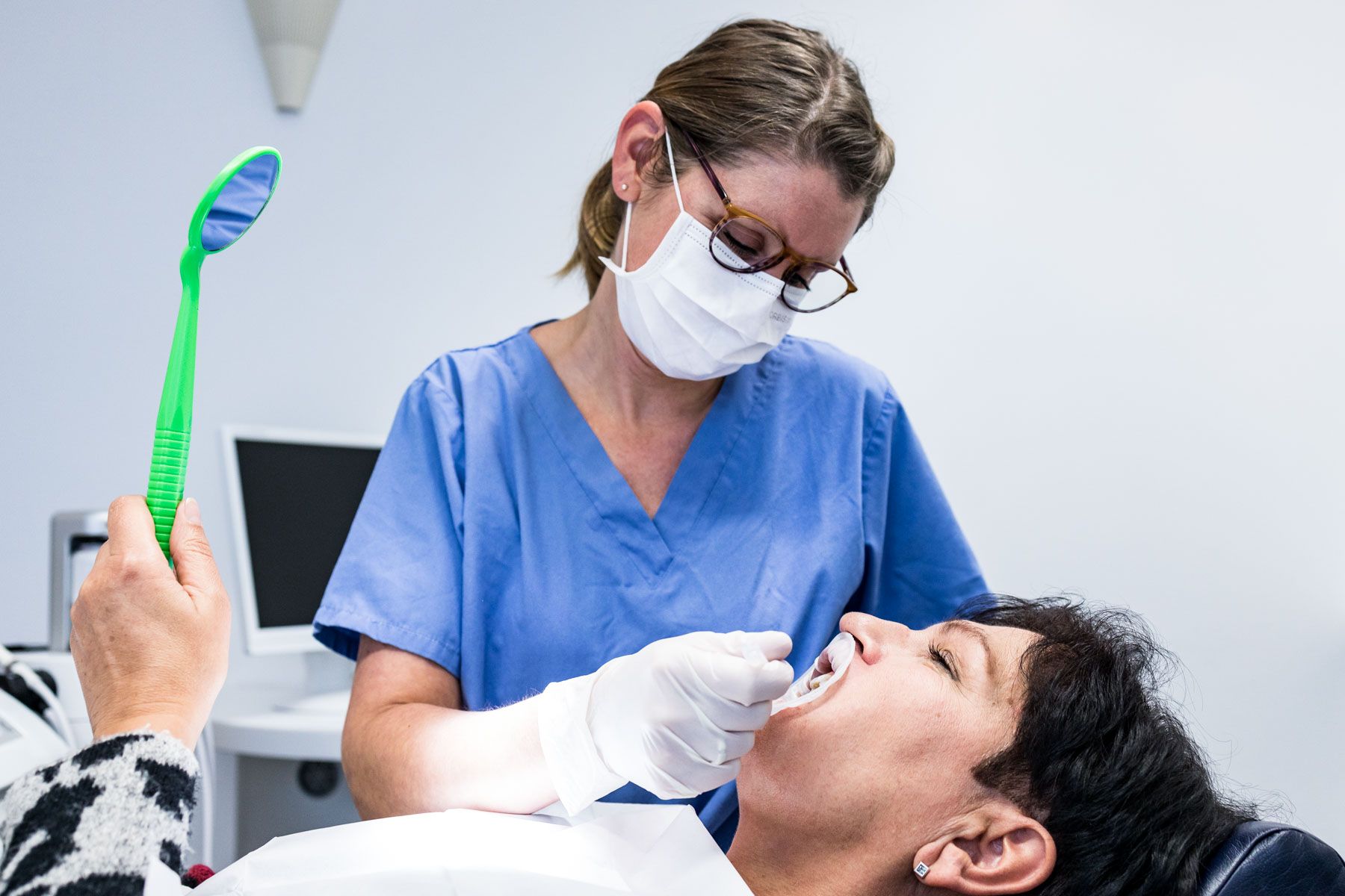 Patientin betrachtet den Stand der Zahnpflege im Spiegel